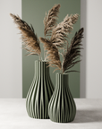 Two black and white striped vases with dried pampas grass against a neutral background
