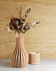 Beige striped vases with dried pampas grass against a neutral background