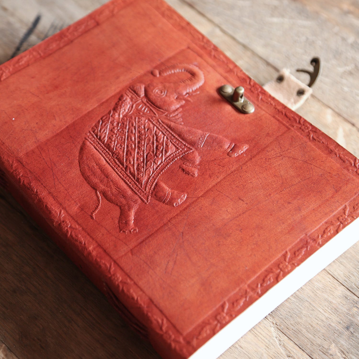 Red leather-bound book with an embossed elephant design on a wooden surface