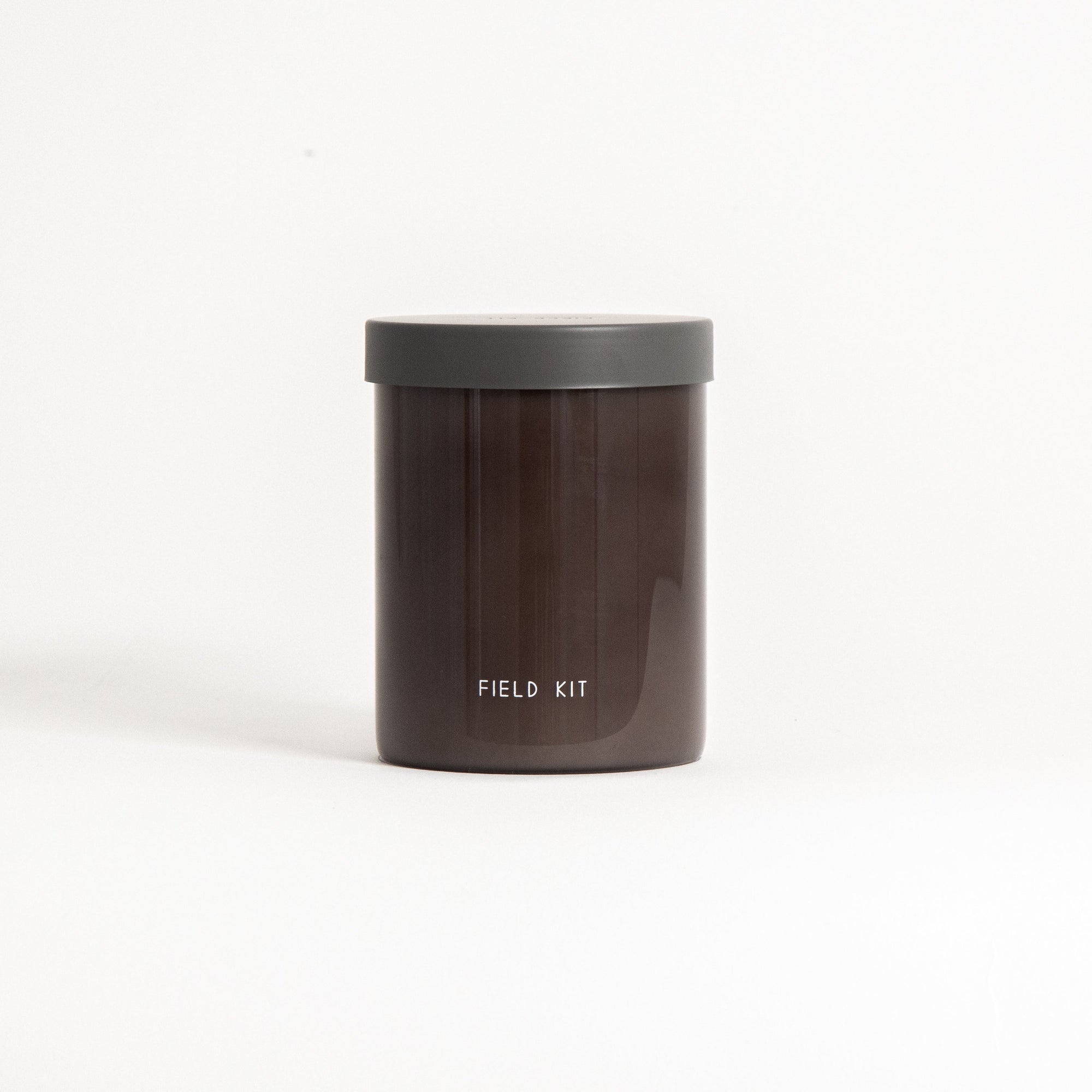A reusable glass jar candle with a dark label and the brand 'Field Kit' visible on the front.