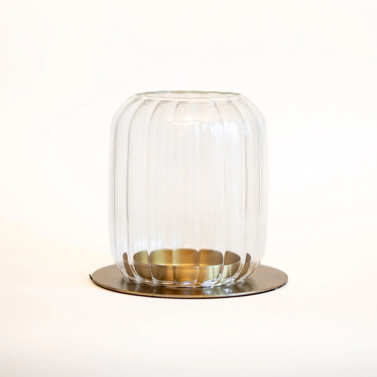 Clear glass lantern with brass base on a white background