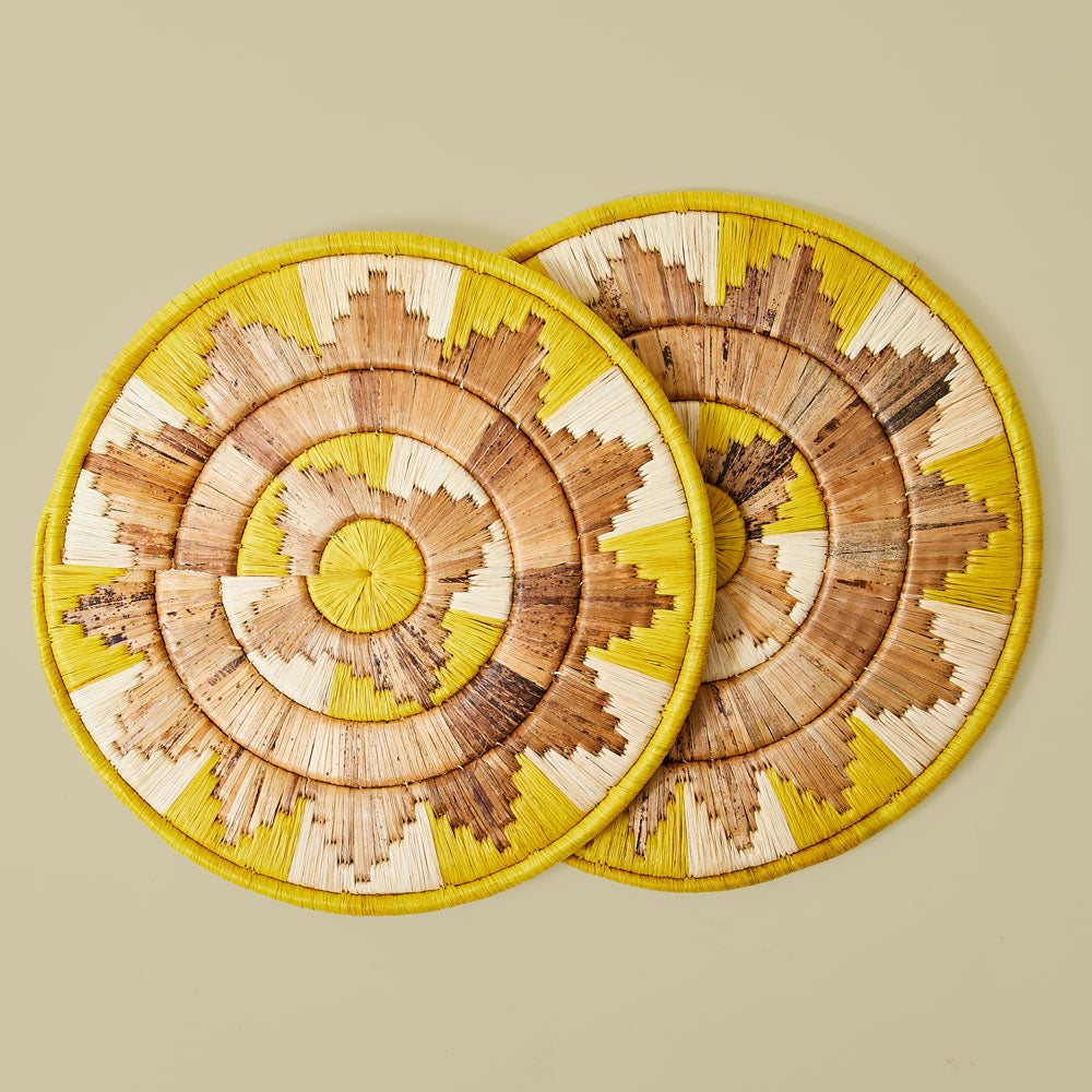 Two woven coasters with a spiral pattern on a yellow background