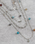 Silver necklaces with beads on a gray surface
