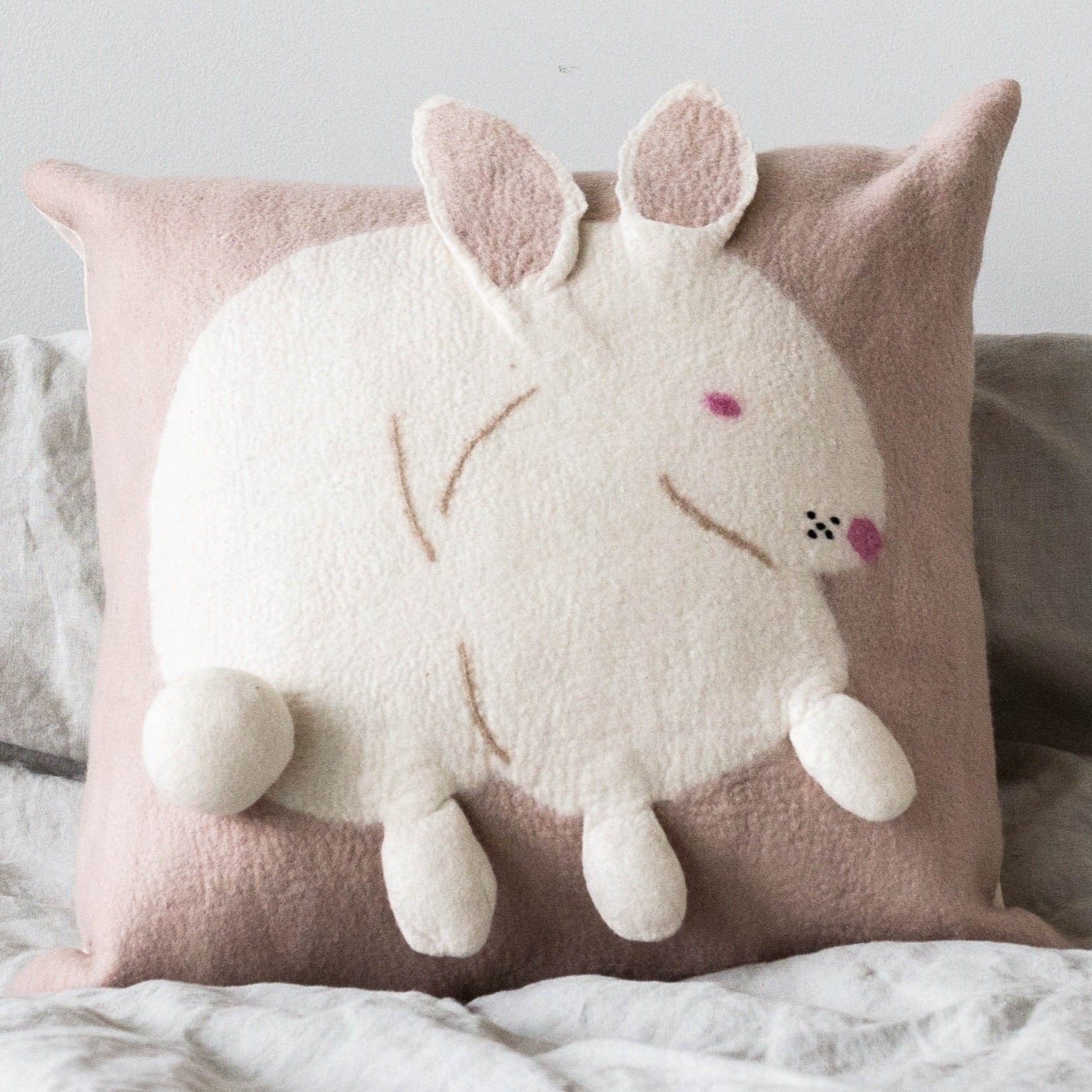Cushion with a white bunny design on a pink background