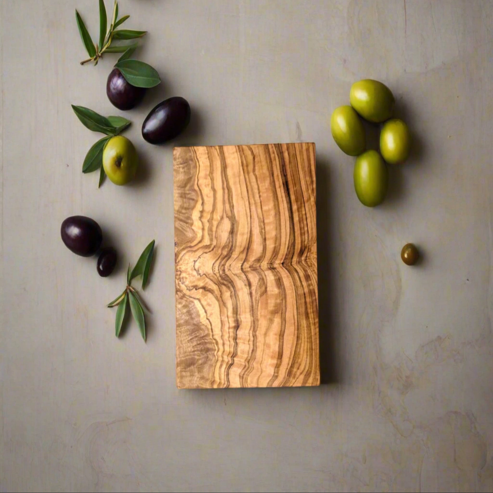 Wooden cutting board with olives on a gray background
