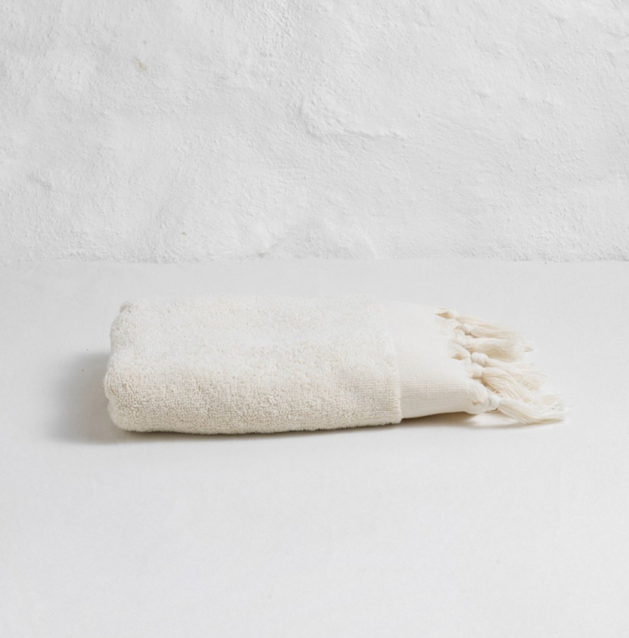Folded beige towel on a light gray background