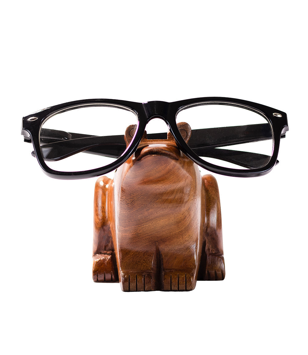 Wooden frog glasses holder with black-framed glasses on a white background