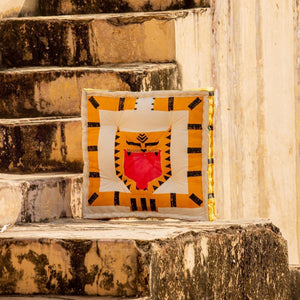 A square-shaped floor cushion with a tiger design, featuring orange and black colors, placed on a staircase with a plain white wall in the background.