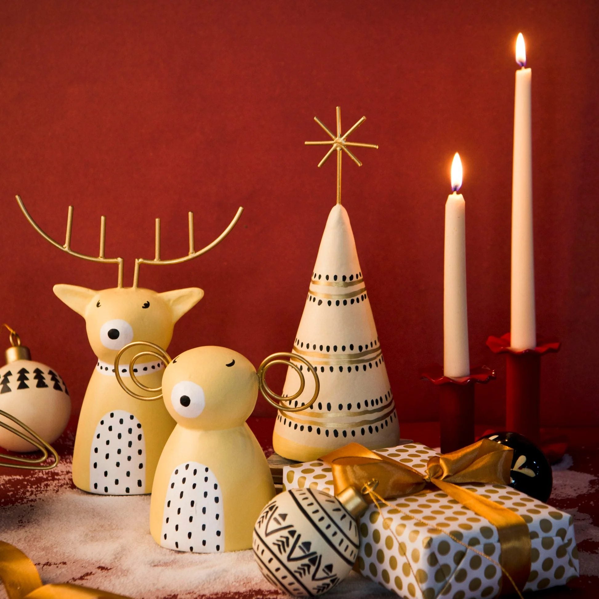 Decorative Christmas scene with reindeer, tree, and presents on a red background