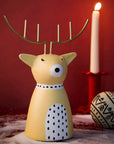 Decorative reindeer figurine with a lit candle on a red background