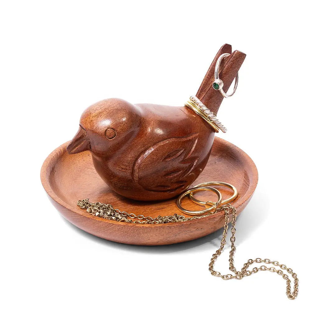 A carved wooden bird-shaped jewelry organizer and tray on a white background, holding gold rings and a chain.