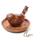 A carved wooden bird-shaped jewelry organizer and tray on a white background, holding gold rings and a chain.