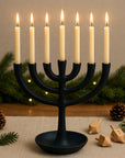 Black menorah with lit candles on a table with Christmas decorations