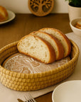 Sliced bread in a woven basket on a wooden table with a knife and fork.