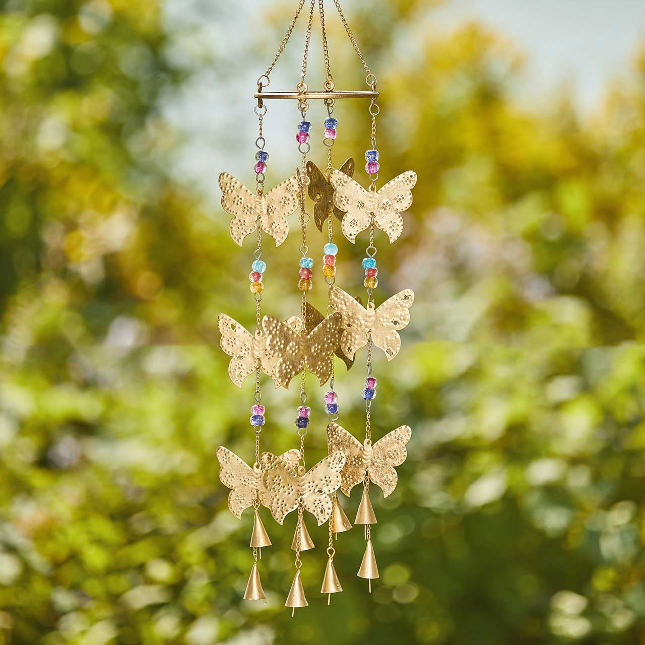 Decorative wind chime with butterflies and beads against a blurred green background