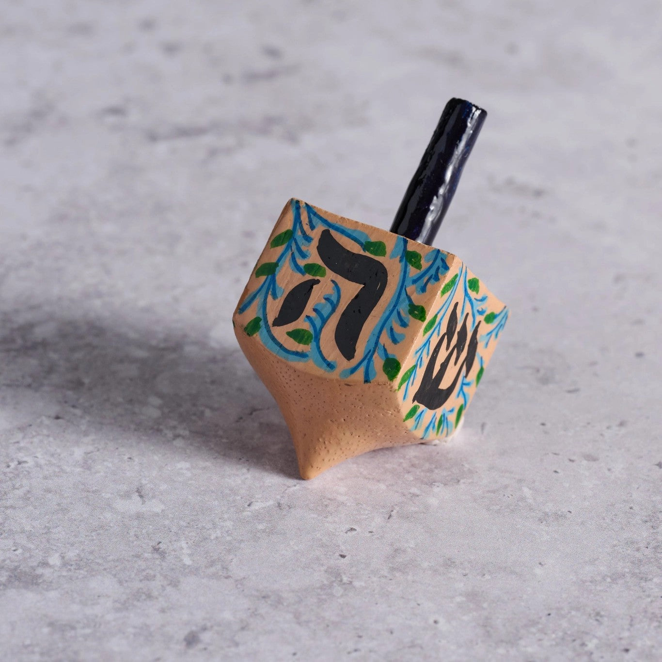 Wooden dreidel with Hebrew letters on a gray surface