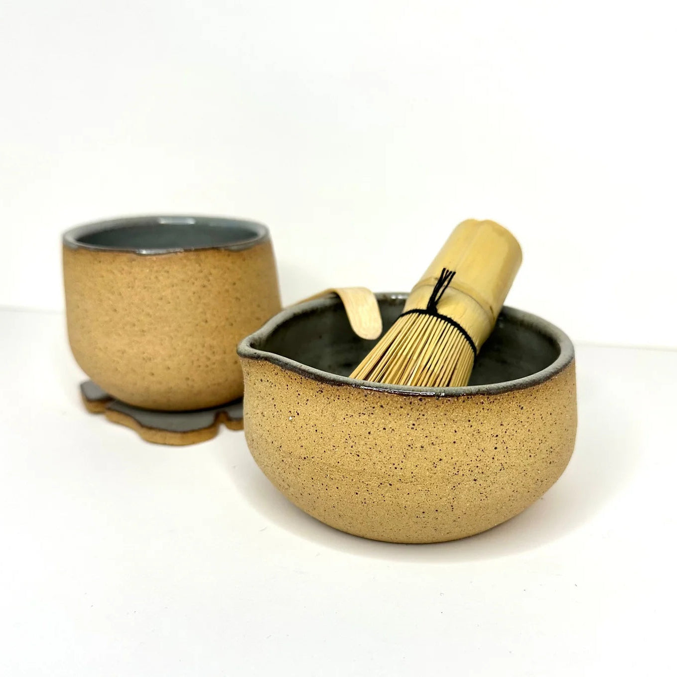Ceramic tea set with two bowls and a whisk on a white background