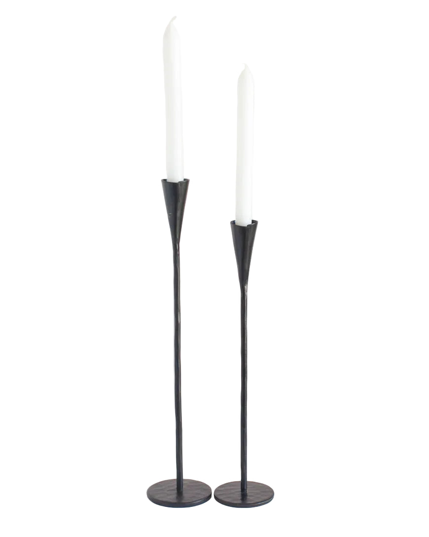 Two black candle holders with white candles on a white background