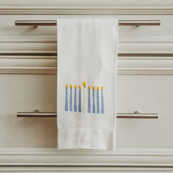 White tea towel with Menorah design hanging on a cabinet door