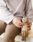 Person holding a wooden elephant ledge lounger with a child's legs and sweater in the foreground.