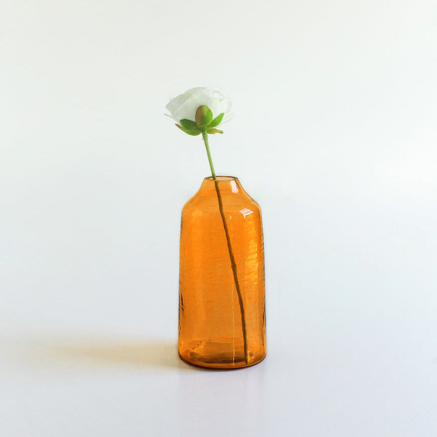 Orange vase with a white flower on a light gray background