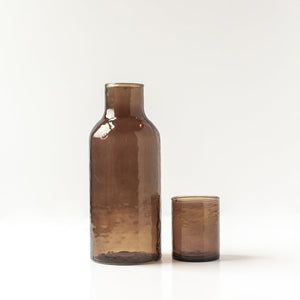 Brown hammered glass carafe and cup on a white background