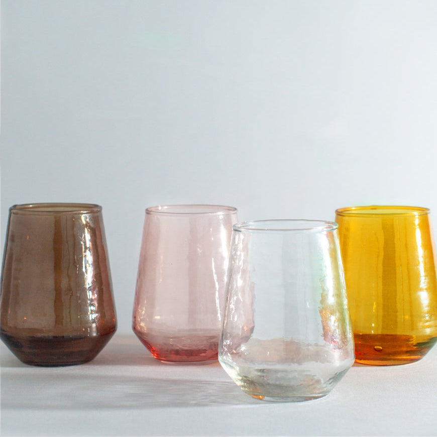 Four colored glass tumblers on a light gray background