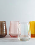 Four colored glass tumblers on a light gray background