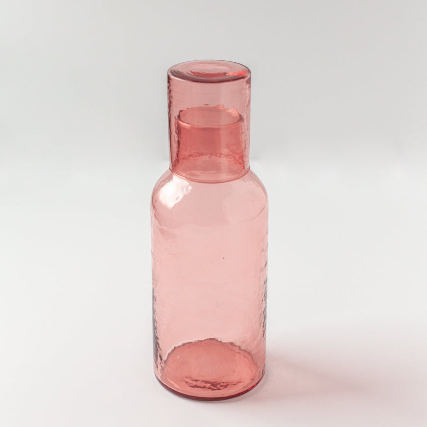 Pink glass carafe on a white background
