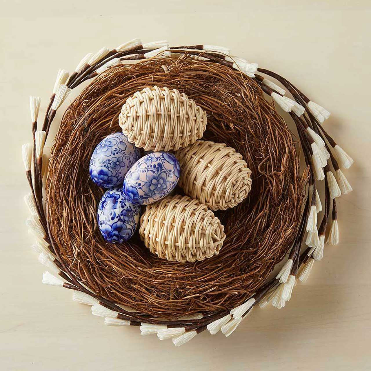 Decorative nest with blue and beige eggs on a beige background