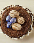 Decorative nest with blue and beige eggs on a beige background