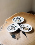 Three small ceramic dishes with floral patterns on a wooden surface