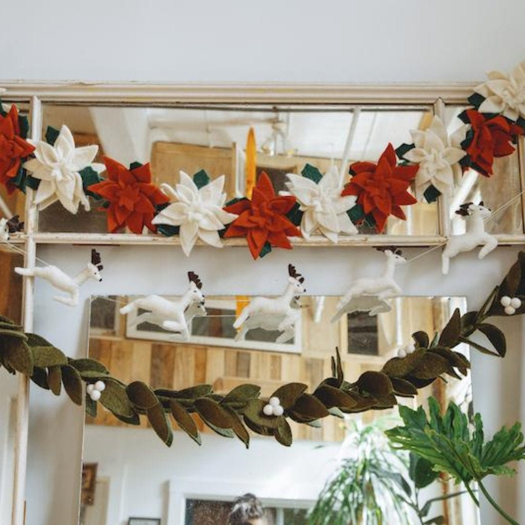 Decorative garland with red, white, and green flowers hanging above a mirror