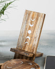 Wooden phone holder with moon phase design on a light gray surface.