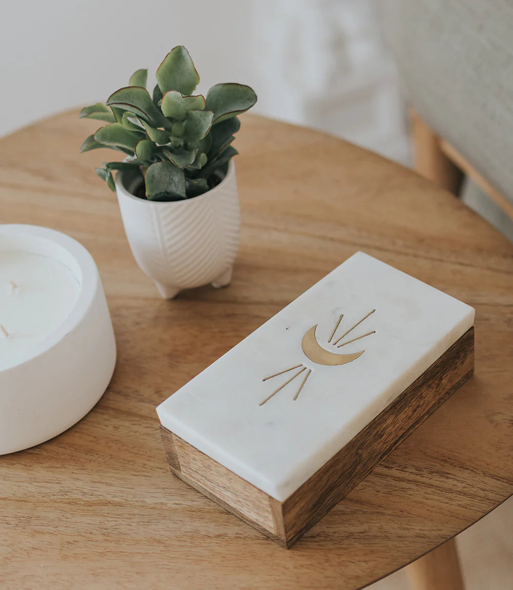 Rectangular wooden block with a decorative design on a wooden surface with a plant and candle