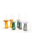 Set of colorful glass candle holders with candles on a white background