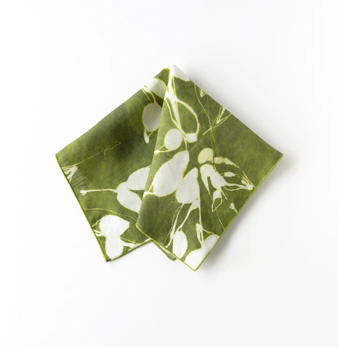 Green napkin with white floral patterns on a white background