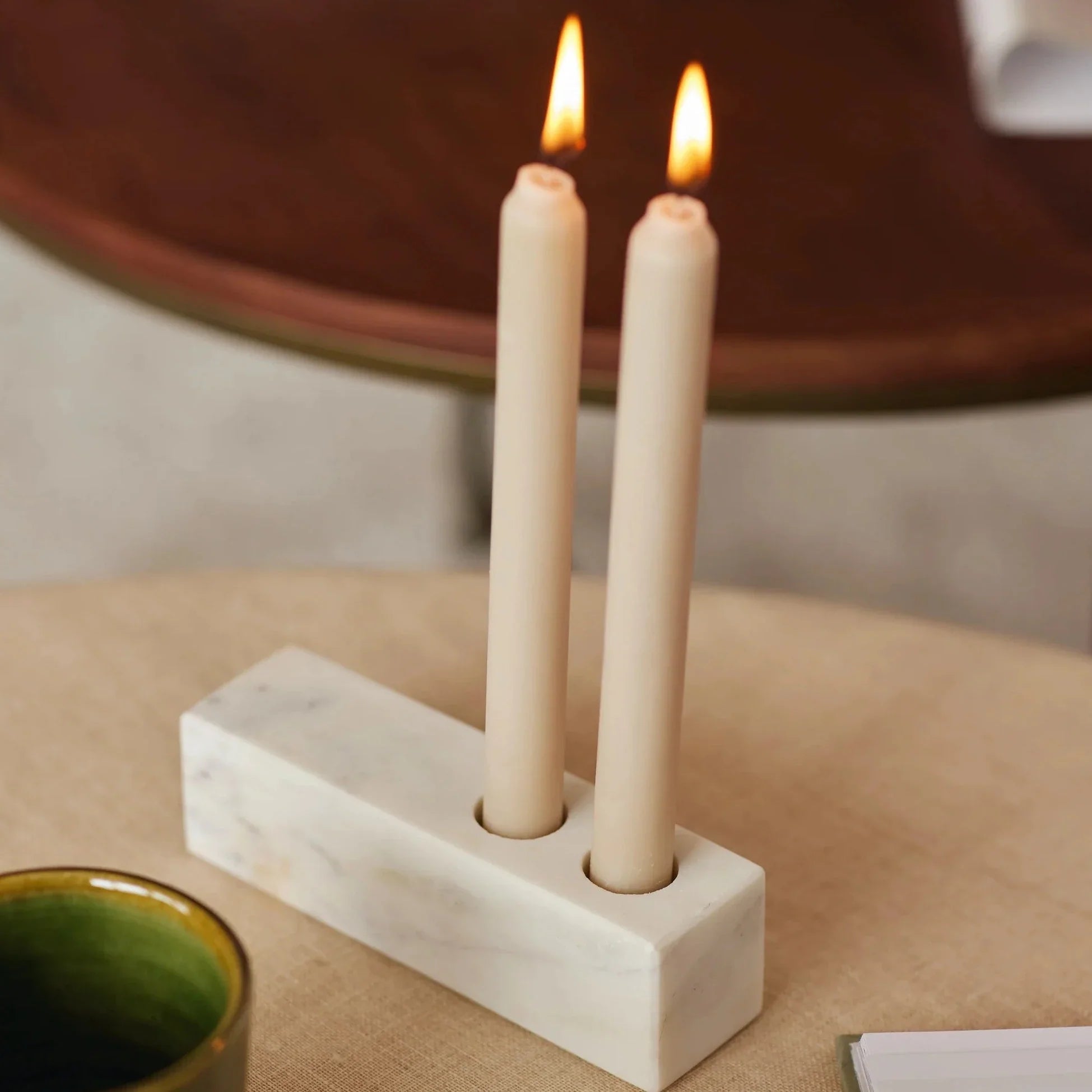 A rectangular marble candle holder with two lit candles