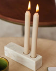 A rectangular marble candle holder with two lit candles