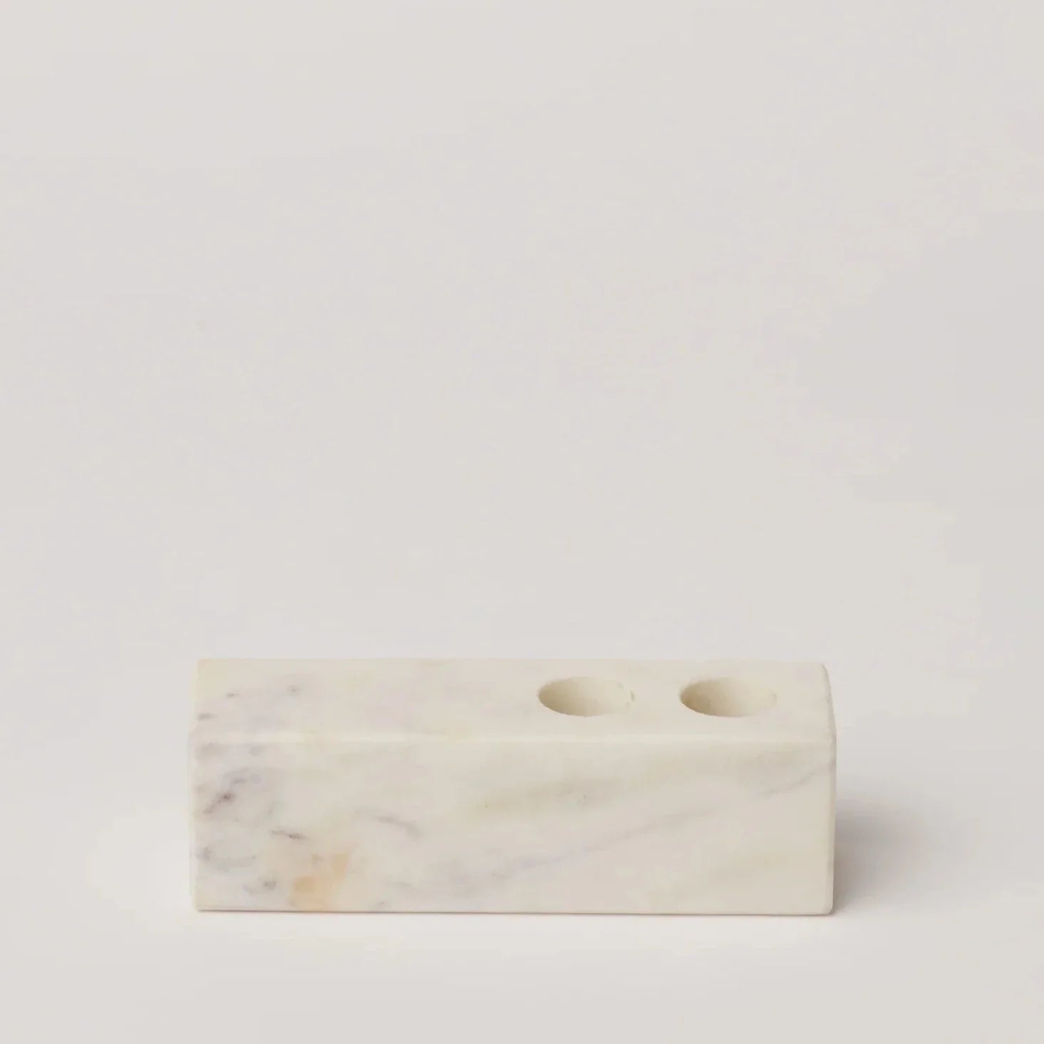 A rectangular marble candle holder with two circular indentations for candles