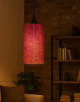 Pink handcrafted beaded pendant light in a cozy room with a bookshelf and plant