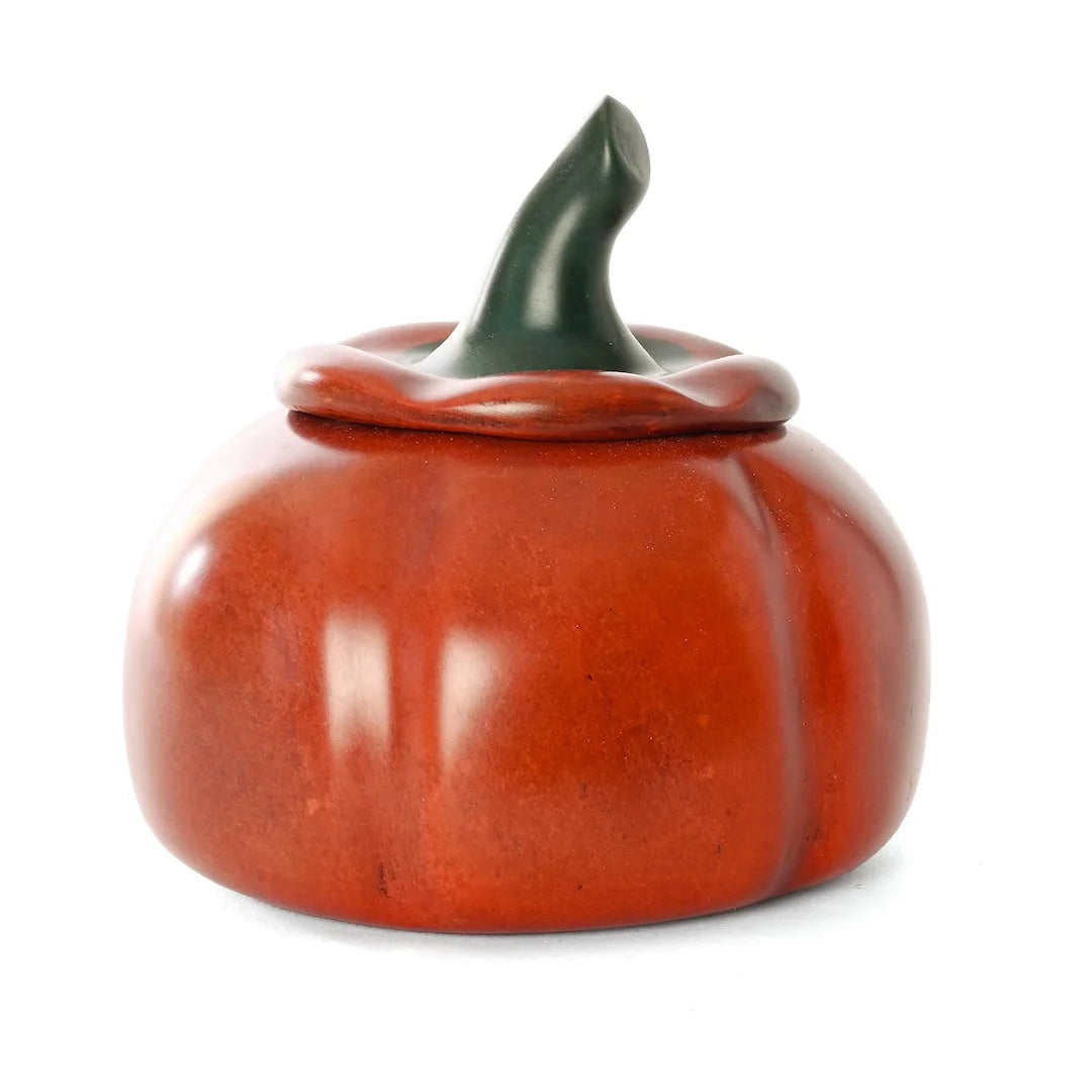 A glossy ceramic pumpkin-shaped container with a matching lid and a dark green stem, shown on a plain white background.