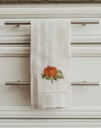 Tea towel with a pumpkin design hanging on a kitchen cabinet