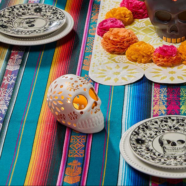 Decorative setup with skull-shaped candles, colorful skulls, and a striped tablecloth.