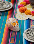 Decorative setup with skull-shaped candles, colorful skulls, and a striped tablecloth.