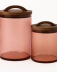 Two glass canisters with wooden lids on a white background