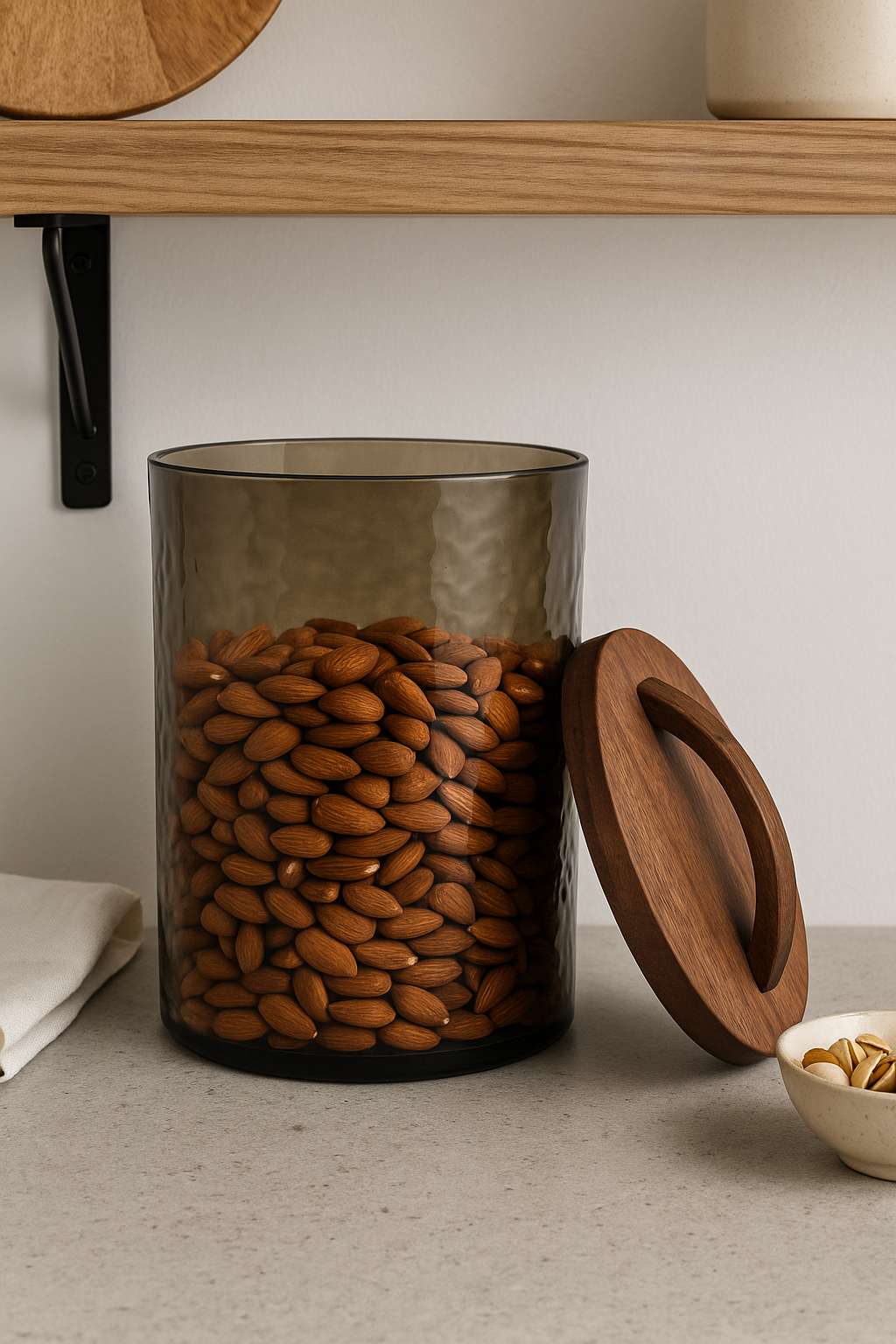 Glass jar with wooden lid filled with almonds on a neutral background