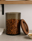 Glass jar with wooden lid filled with almonds on a neutral background