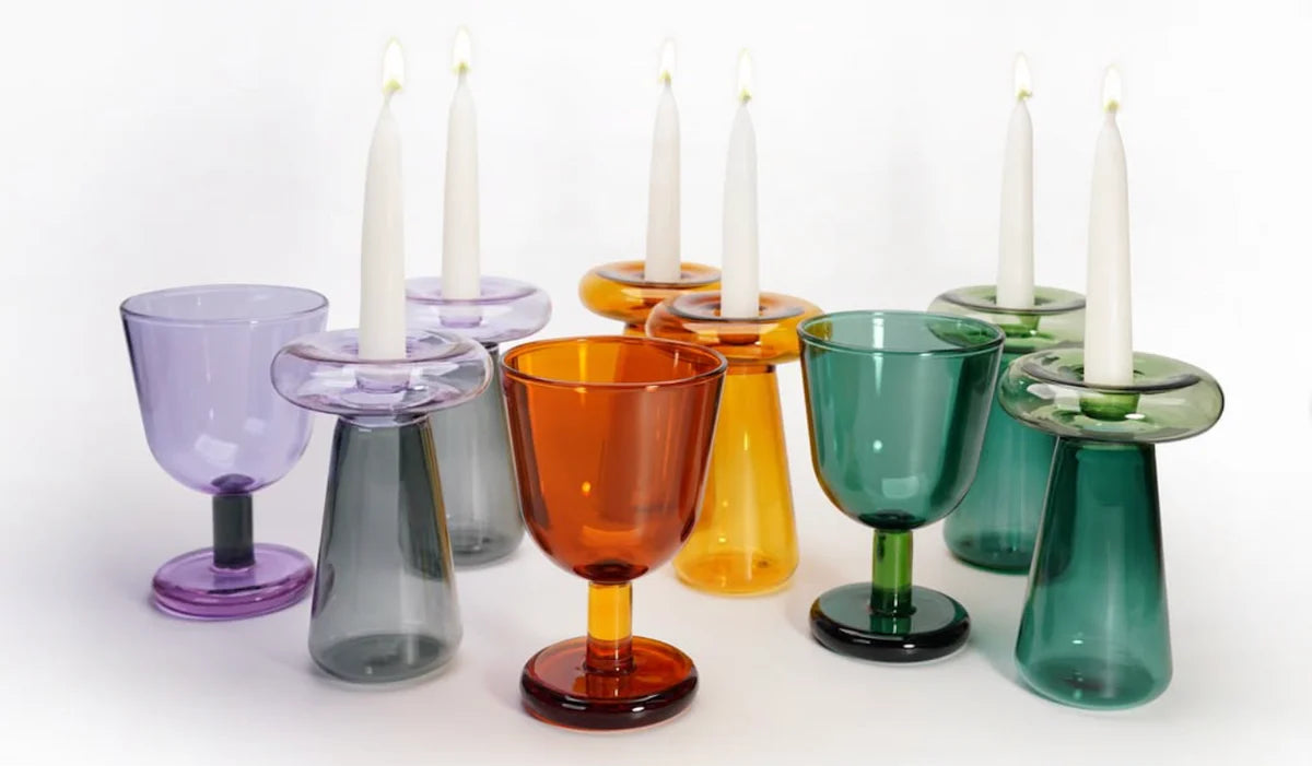 Colorful glass candle holders with white candles on a white background