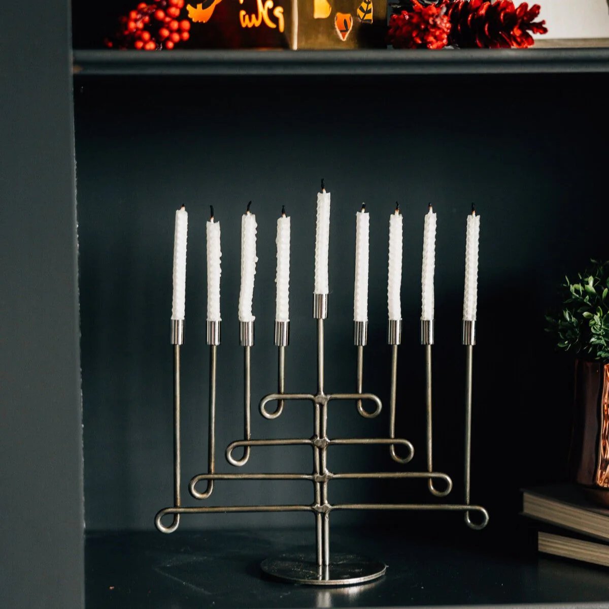Decorative menorah with white candles on  a shelf with a dark background